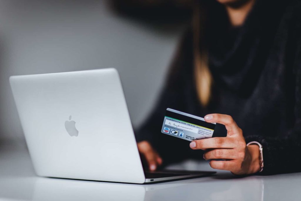 woman holding black smartphone near silver macbook